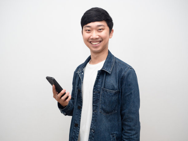 快乐的男人牛仔裤衬衫微笑拿着智能手机图片下载