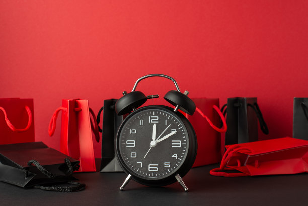 星期一的概念。照片闹钟红色和黑色纸袋黑色桌面红色墙壁背景图片下载