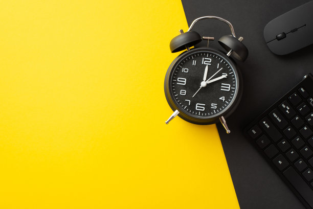 星期一的概念。俯视图照片的键盘，电脑鼠标和黑色闹钟在双色黄色和黑色的背景与空白图片下载