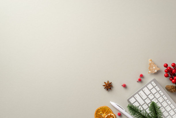 新年的概念。顶视图照片工作站键盘钢笔圣诞树木材装饰槲寄生浆果松枝干橙片和八角上孤立的灰色背景与copyspace图片下载