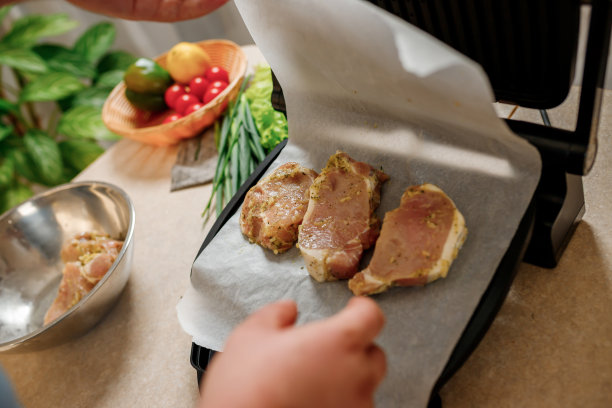 男人的手准备美味多汁的肉排在电烤架上的木桌。在家里的厨房抽烟图片下载