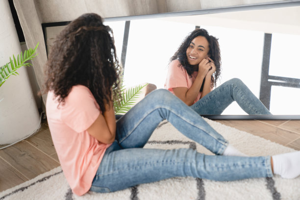 快乐的年轻非洲妇女女孩戴上耳环，准备活动会议日期，看着镜子在家里图片下载
