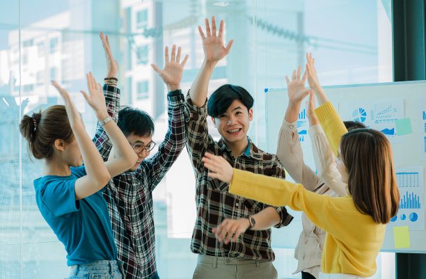 祝新一代亚洲商业女性和男性快乐。身着正式服装的成功女商人、雇员和同事，通过握手和举起拳头一起庆祝活动的成功图片下载