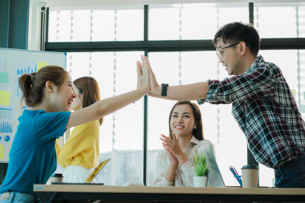 祝新一代亚洲商业女性和男性快乐。身着正式服装的成功女商人、雇员和同事，通过握手和举起拳头一起庆祝活动的成功图片下载