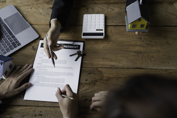 一对年轻的已婚夫妇正在与房地产经纪人商谈签订购房合同。图片下载