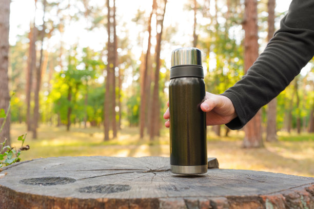 一个人把一个热水瓶放在树桩上图片下载