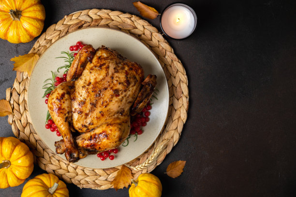 感恩节烤鸡：黑桌上的烤鸡或火鸡与香草迷迭香、浆果和南瓜感恩节晚餐，节日餐桌布置图片下载