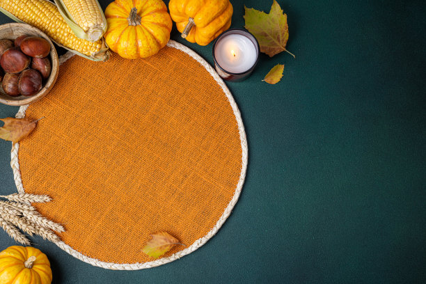 顶视图柳条橘席，南瓜，收获玉米，栗子，秋叶，蜡烛在黑暗的桌子上。餐厅菜单。秋季背景的餐桌设置图片下载