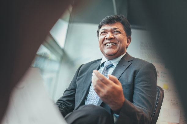 亚裔印度成熟商人穿着西装在商务办公室开会时与同事有说有笑图片下载