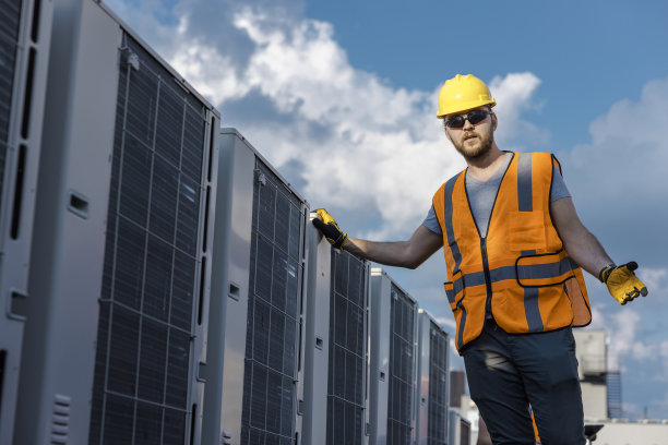 蓝领工人，专业技术人员，在屋顶的空调旁边摆姿势。图片下载