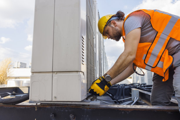 在屋顶上，一名蓝领工人正在修理空调设备。图片下载