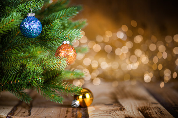 木制桌子上有装饰品的圣诞树和散焦灯图片下载