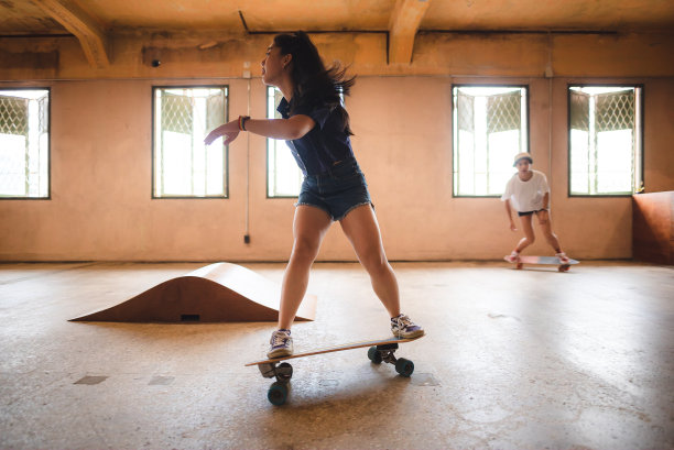 滑板运动的生活方式，年轻的亚洲滑冰妇女与一个板在健身房有乐趣图片下载
