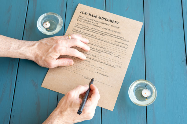 男子用钢笔在点燃的蜡烛旁签署合同。图片下载