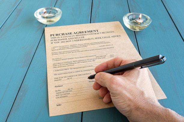 男子用钢笔在点燃的蜡烛旁边签署合同。图片下载