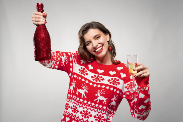 有趣的女人在灰色背景下举起一瓶香槟庆祝平安夜图片下载