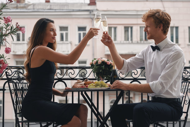 年轻相爱的夫妇在阳台上喝着香槟，吃着浪漫的晚餐图片下载