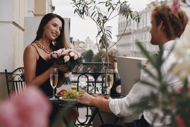迷人的年轻女子拿着花束，与她的男朋友正在吃浪漫的晚餐图片下载