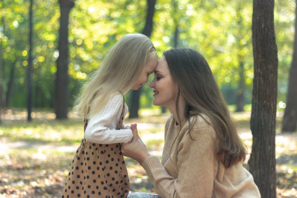 妈妈和女儿手牵着手。照片在概要文件。他们把额头靠在额头上。家人走。快乐的母女。绿色公园。家庭价值观。温柔和爱。图片下载