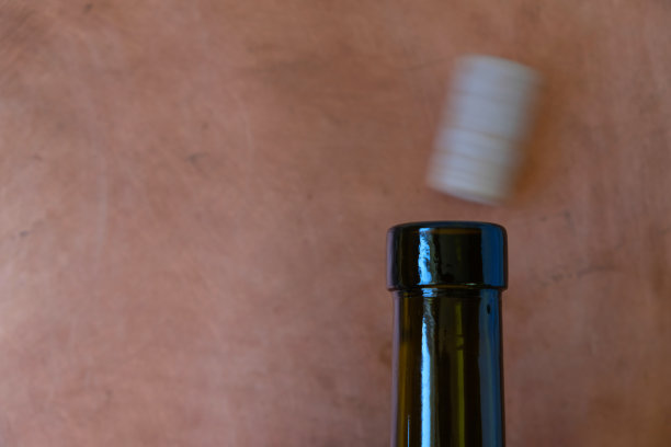 空酒瓶的瓶口和模糊的软木塞在铜背景上运动。图片下载