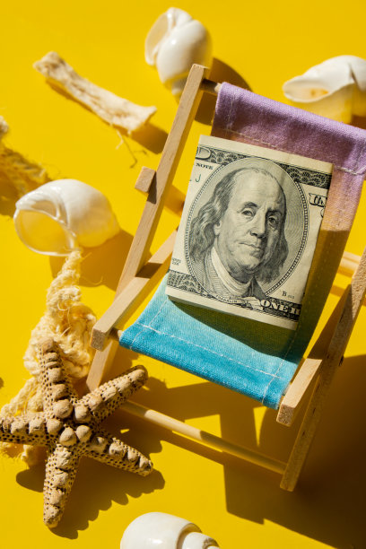 卷起来的一百美元钞票在微型甲板沙滩椅。旅游假期成本的概念。除了假期。本空间图片下载