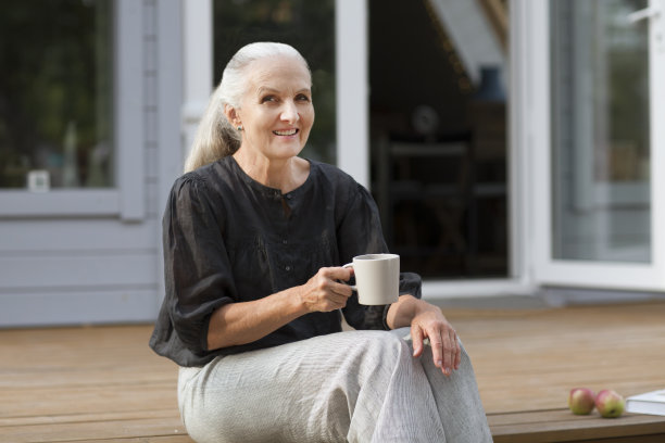 一个快乐的老妇人在她家附近的花园里喝茶的画像。概念没有压力。心理健康。心理健康。享受小事。图片下载