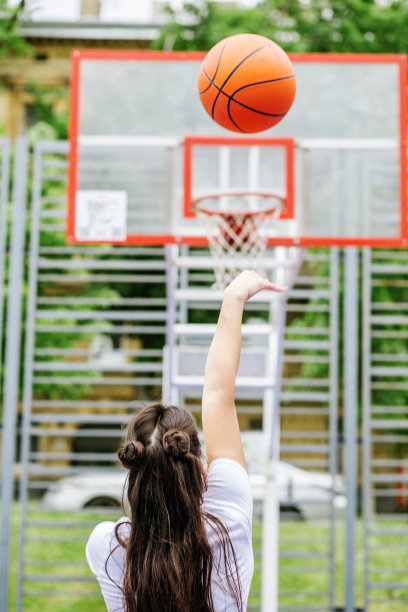 年轻的女运动员正在现代化的户外篮球场训练打篮球。图片下载