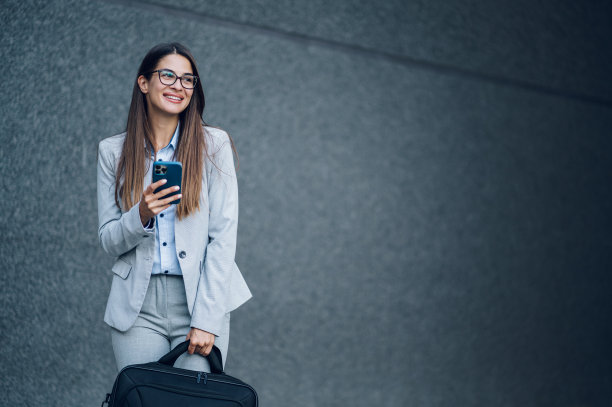 商业女性站在办公楼外使用智能手机图片下载