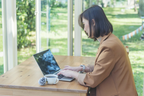 靠近女商人手打字笔记本电脑喝黑咖啡杯在绿色花园咖啡馆。汉兹女士喜欢在家工作时喝热咖啡。商务女士要黑咖啡或热巧克力咖啡图片下载