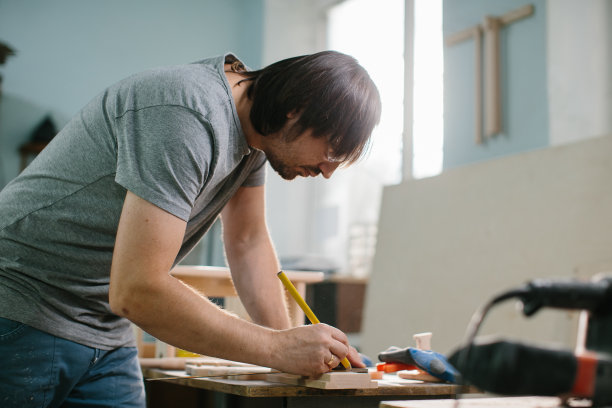 木匠在木匠铺的木桌上操作设备。图片下载