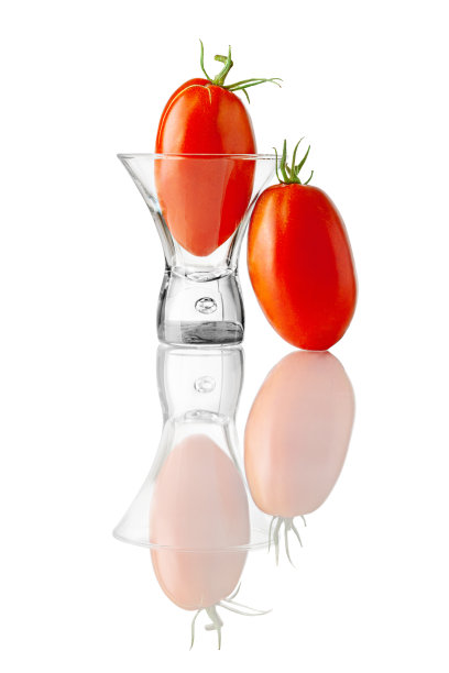 两个成熟的椭圆形西红柿和玻璃杯的静物画。工作室拍摄与充分的自然反射隔离在白色背景。图片下载