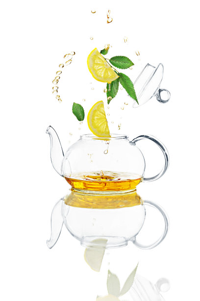 飞舞的绿叶，柠檬片，茶壶盖，清澈的液体溅在透明的茶壶。悬浮的概念，工作室拍摄与自然反射。图片下载