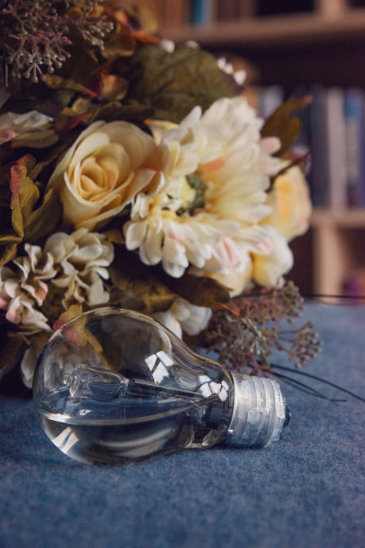 装满水的灯泡放在蓝色毯子上，上面有复古的花束，垂直的图片下载