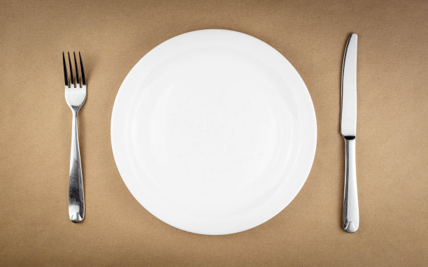 空盘子与叉和刀隔离在棕色再生纸背景与复制空间图片下载