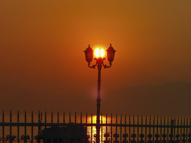 夏天，太阳出现在灯柱栅栏之间图片下载