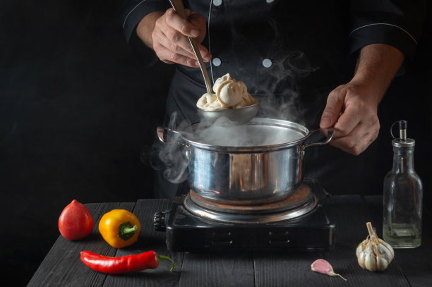 厨师在餐厅厨房用平底锅煮肉馅饺子。厨师工作时的手特写。免费的广告空间。图片下载