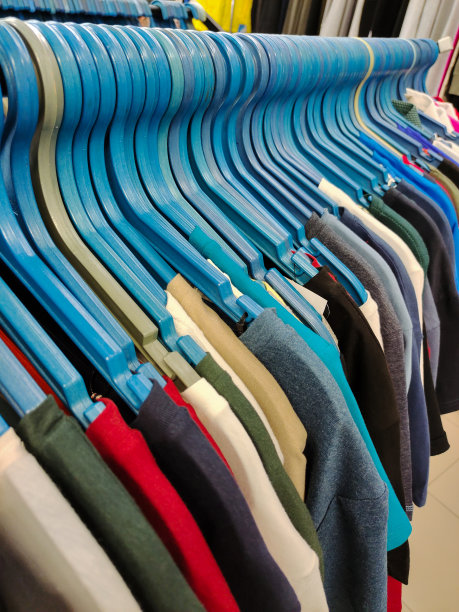 在一家服装店里，一排排衣架上挂着各种颜色的长袍和衬衫图片下载