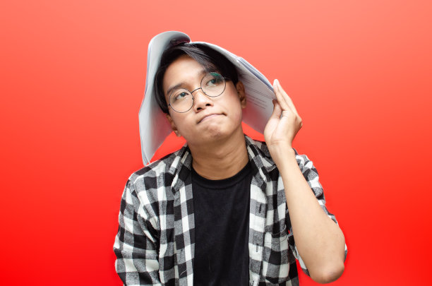 愤怒和厌倦的亚洲男子学生持有论文论文工作孤立在红色背景。图片下载