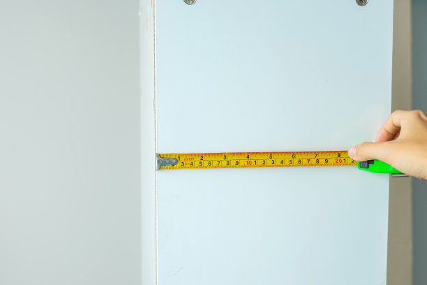 用卷尺测量家里的家具。DIY，室内设计，维修和改善家庭或公寓概念图片下载