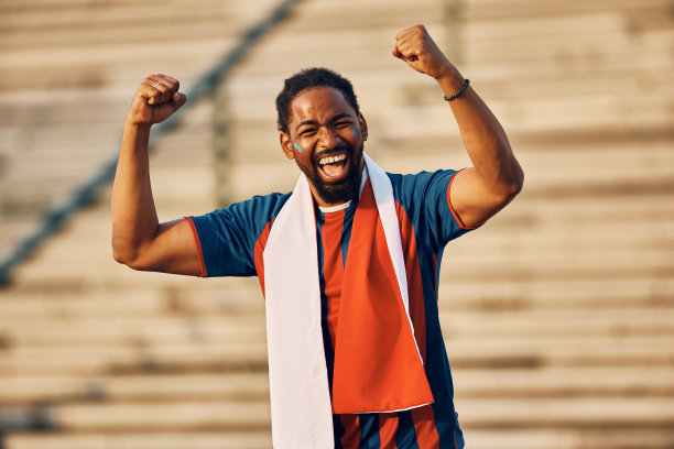 兴奋的黑人体育迷在户外庆祝，看着相机。图片下载