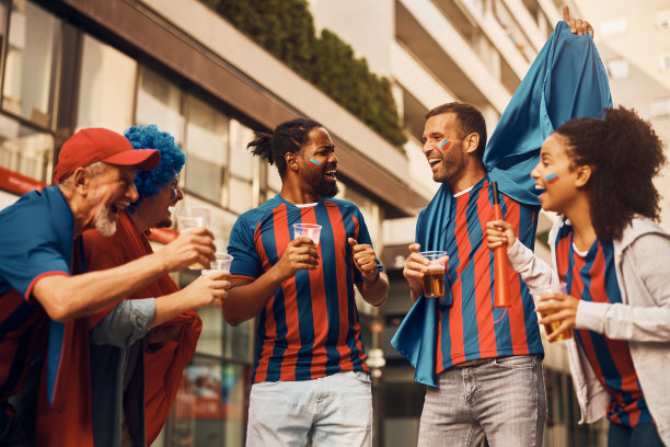 多种族的快乐球迷在街上喝着啤酒庆祝。图片下载