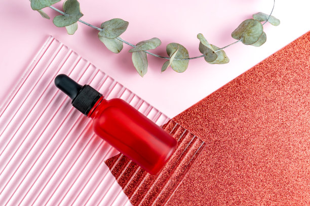 产品照片。模型的脸血清瓶空白标签上的粉红色和闪闪发光的红色背景。美容理念，面部护肤。海洋成分抗衰老护理产品广告图片下载