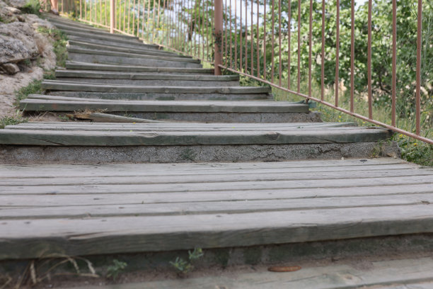 在阳光明媚的日子里，木质楼梯沿着草坡向上延伸图片下载