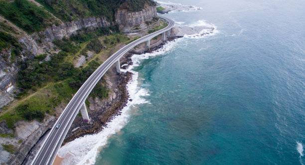 无人机在岩石海岸上拍摄的沥青公路桥图片下载