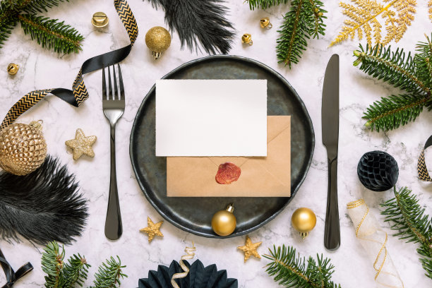 黑色和金色的圣诞餐桌设置与卡片，饰品和杉树树枝。模型图片下载