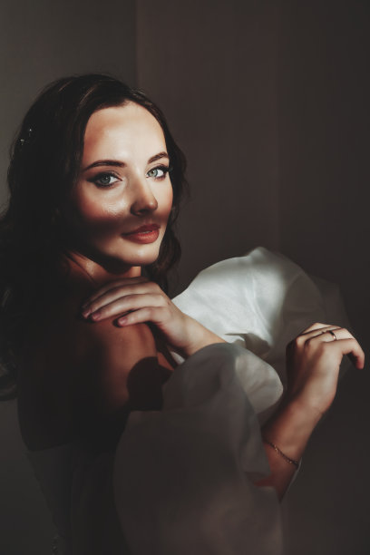 肖像时尚的新娘年轻女子在白色婚纱站在阴影，看着相机。新娘女士在复古的房间，灰色的墙背景在工作室。时尚风格的概念。复制文本空间图片下载