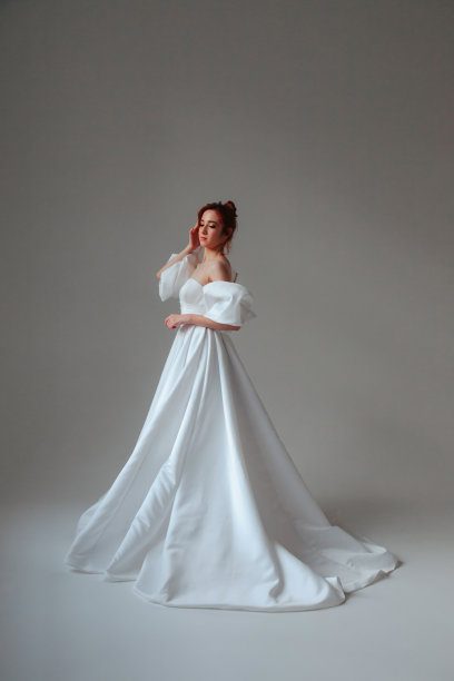 全长时尚的德国新娘年轻女子在白色婚纱站着，闭着眼睛。新娘女性在工作室的灰色墙壁背景上的复古房间。时尚风格的概念。复制文本空间图片下载
