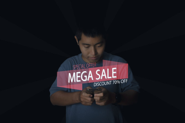 年轻人使用智能手机在网上购物与MEGA SALE折扣横幅推广。图片下载