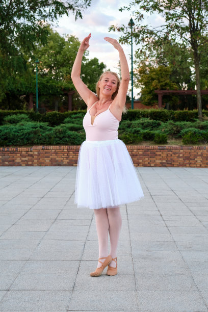 一个成熟的女人在街上的公园里跳芭蕾。图片下载