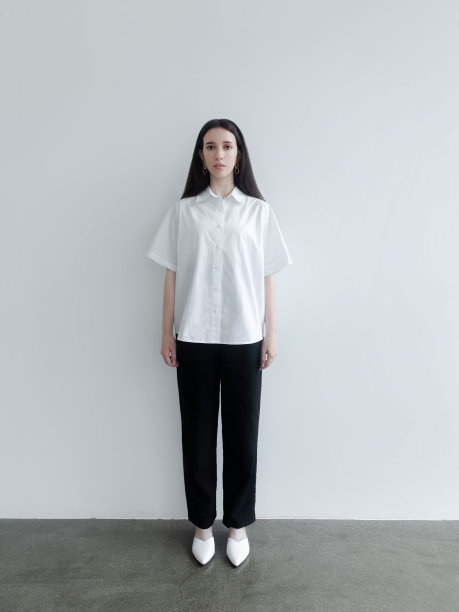 年轻美丽的女人在简单的经典衣服白色短袖衬衫鞋子黑色裤子前视图站立不动时尚模特工作室肖像在光背景图片下载